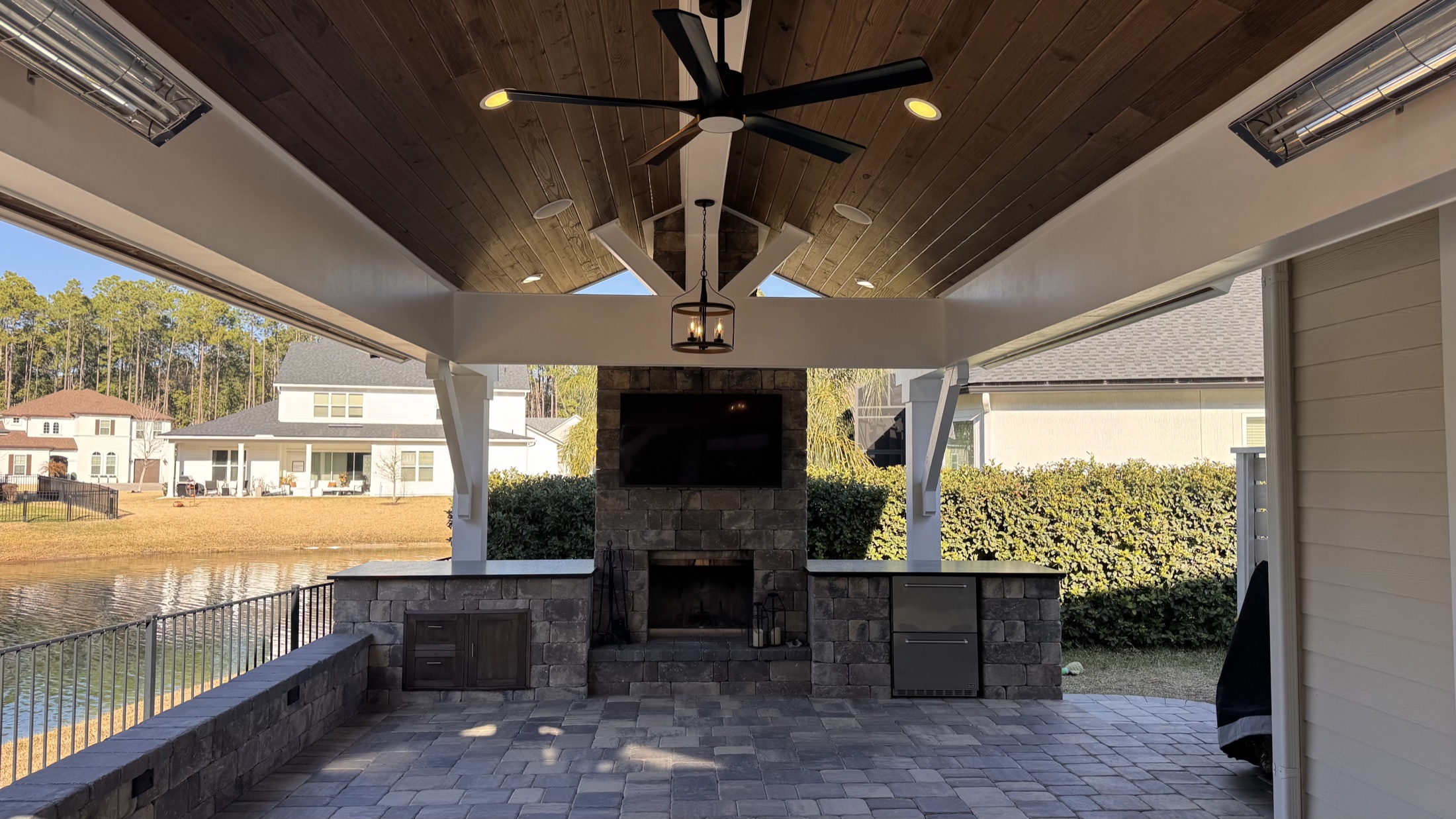 Completed outdoor kitchen beneath a tongue-and-groove patio cover overlooking a pond