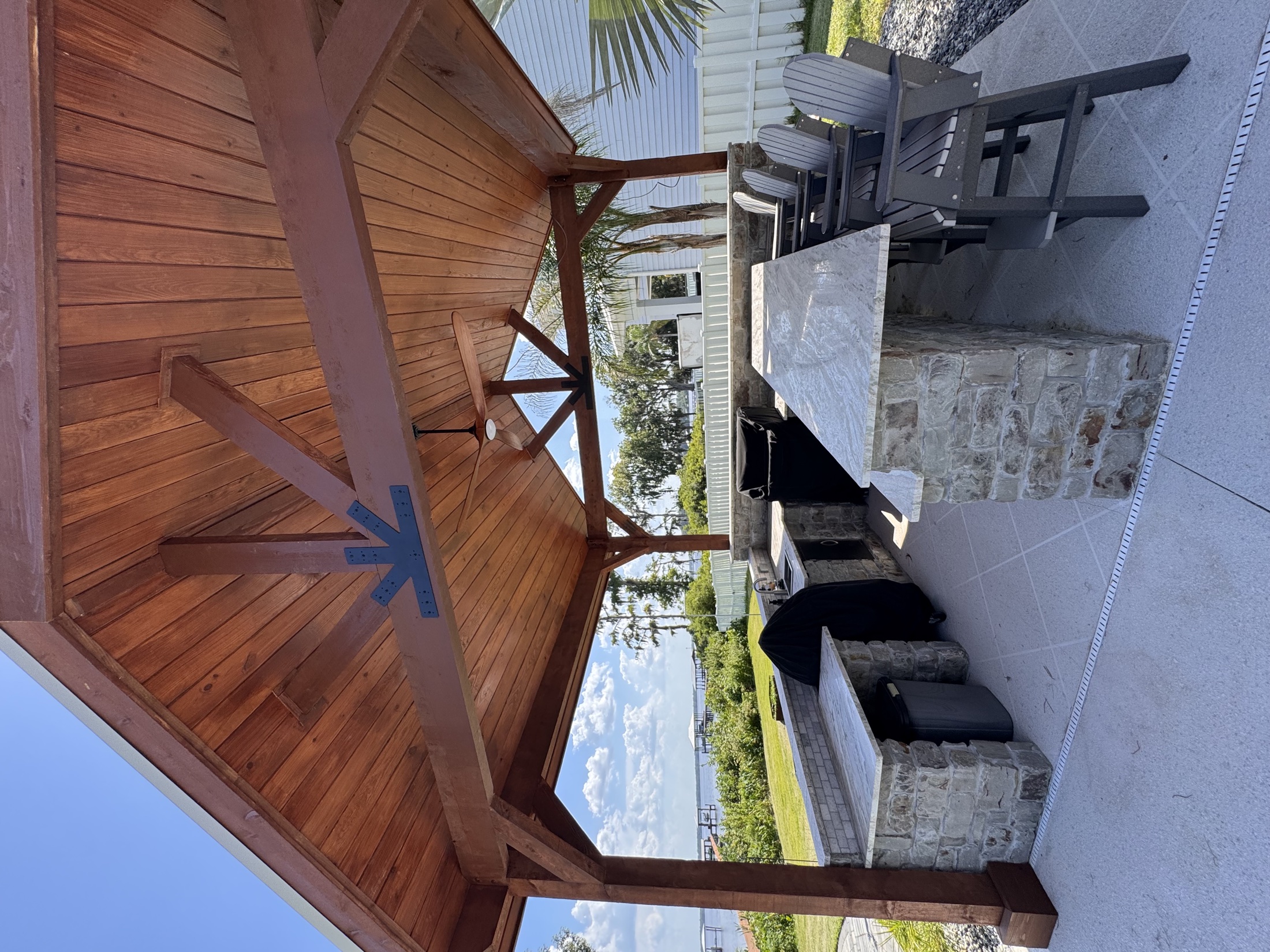 Completed wood pavilion and stone outdoor kitchen overlooking the water